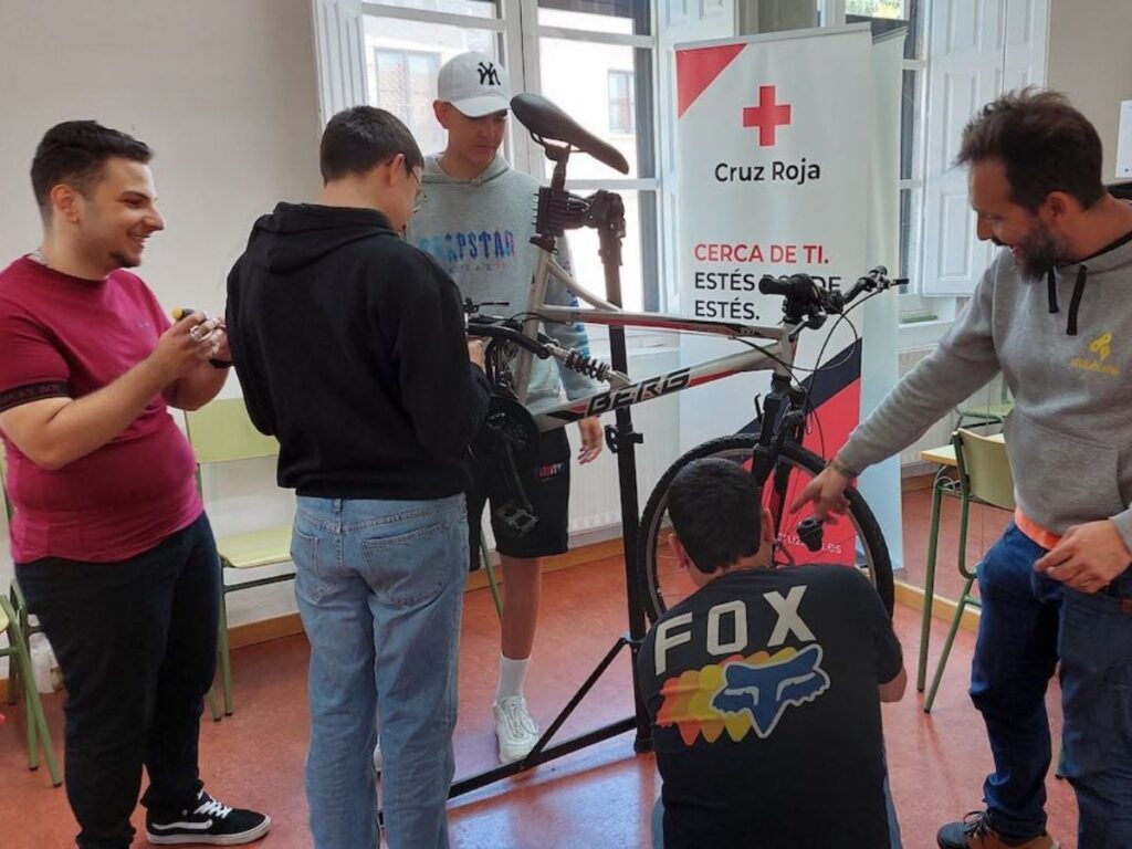 Grupo aprende mecánica básica en bicicleta montada en soporte, en taller práctico de servicio técnico en Colombia.